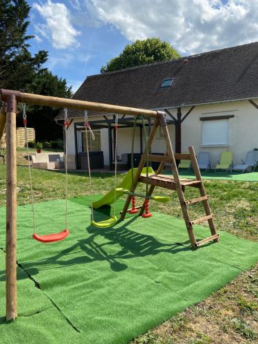 a playground with a swing set on a lawn at La Charmeraie : Le Logis in Thésée