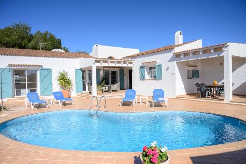 a swimming pool with blue chairs and a house at Quite villa with private pool in Binibeca in Binibeca