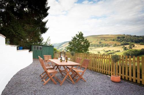 a wooden table with chairs and a fence at Hillside Cottage, countryside views near Llangollen in Corwen