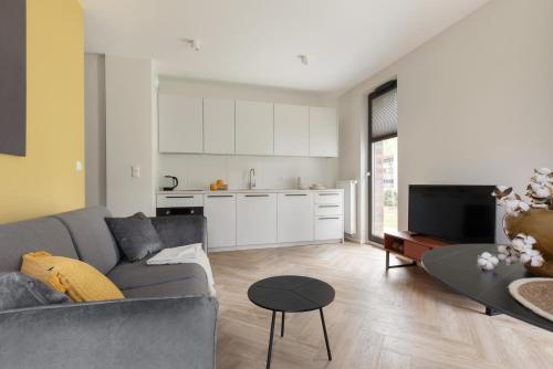 a living room with a couch and a table and a kitchen at Glow Apartments, Aparthotel Kołłątaja - Wrzeszcz in Gdańsk