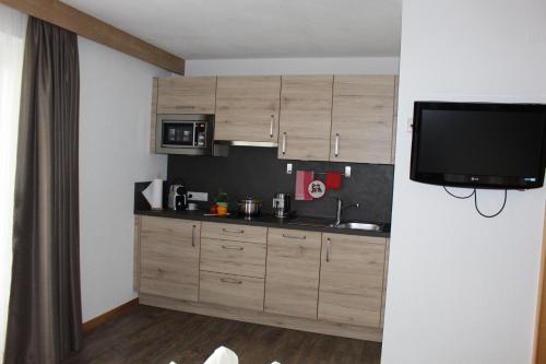 a kitchen with wooden cabinets and a flat screen tv at Sportpension Rubin in Sölden