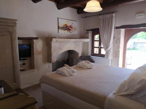 um quarto com uma cama com lareira e uma televisão em Wild Violet Villa: an old vision of luxury em Melidhónion