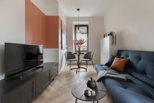 a living room with a blue couch and a tv at Glow Apartments, Aparthotel Kołłątaja - Wrzeszcz in Gdańsk
