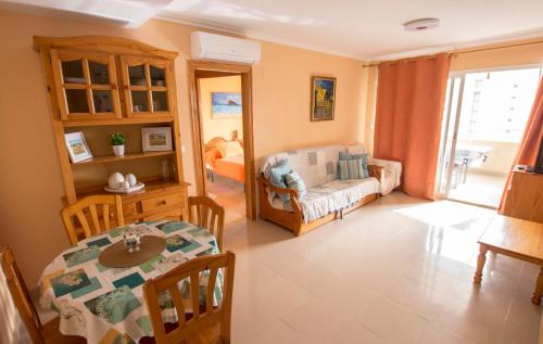 een woonkamer met een tafel en een eetkamer bij Bonito apartamento cerca de la playa, planta alta. in Cala de Finestrat