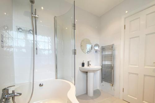 a white bathroom with a shower and a sink at STUNNING LODGE MINUTES FROM THE SEA AND GOLF COURSE in Longniddry