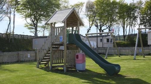 einen Spielplatz mit Rutsche und Spielstruktur in der Unterkunft Kittiwake in Saint Cyrus