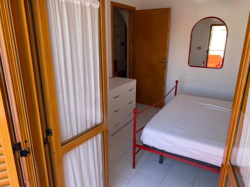 ein kleines Schlafzimmer mit einem Bett und einem Spiegel in der Unterkunft Un Raggio di Sole in Scalea