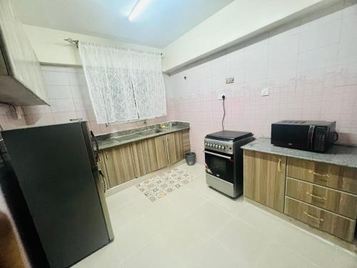a kitchen with a stove and a microwave in it at Eastleigh Executive Furnished Apartments next to BBS Mall in Nairobi