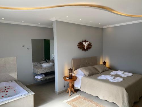 a bedroom with a bed and a tub and a sink at Pousada Maria Monteiro Tiradentes in Tiradentes
