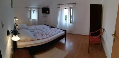 ein Schlafzimmer mit einem großen Bett und einem Stuhl in der Unterkunft Apartman Kornu in Veli Lošinj