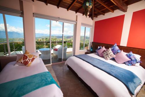 two beds in a room with large windows at Hotel Mansión Barichara in Barichara