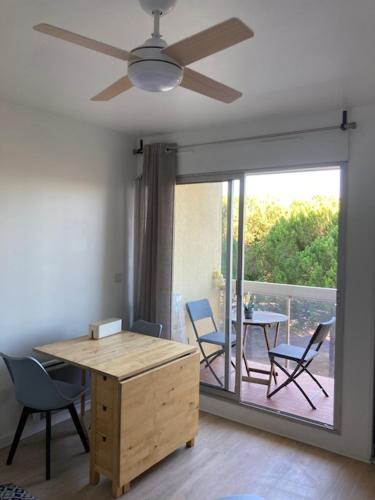 Cette chambre dispose d'un ventilateur de plafond, d'une table et de chaises. dans l'établissement Charmant studio refait à neuf CARNON port 34, à Mauguio