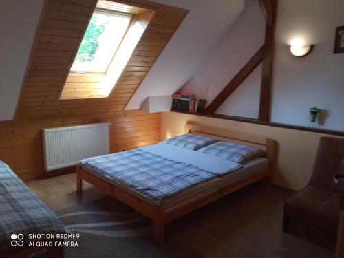 sypialnia z łóżkiem na poddaszu z oknem w obiekcie Domek i Apartamenty Stokrotka w mieście Krynica Zdrój