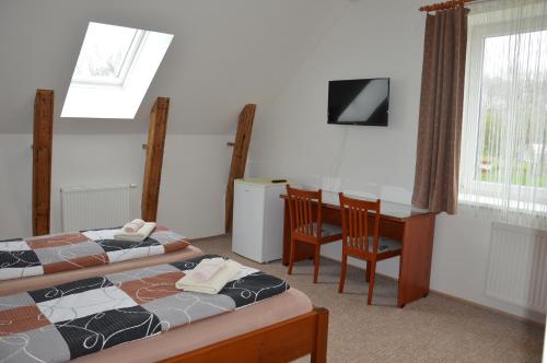 a room with two beds and a desk and a table at Penzion Alma in Znojmo