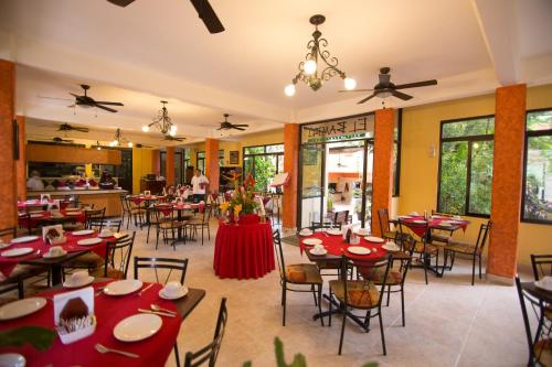 a restaurant with tables and chairs with red tablecloths at Hotel Maya Tulipanes Palenque in Palenque