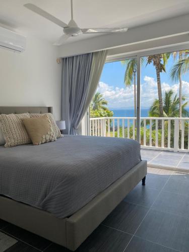 a bedroom with a bed and a balcony with the ocean at Vista Mare Samana Amazing Views!! in Santa Bárbara de Samaná