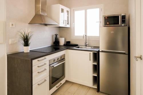 a kitchen with white cabinets and a stainless steel refrigerator at Casa MyA con terreno privado y parking compartido - a 800m de Playa Poniente in Benidorm