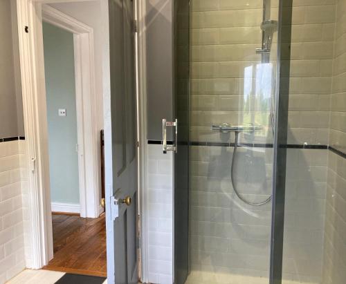 a shower with a glass door in a bathroom at Large House On Farm With Own Heated Pool, As Seen On BBC TV in Cullompton