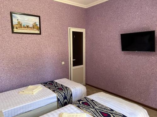 a room with two beds and a tv on the wall at Guest House Han in Samarkand