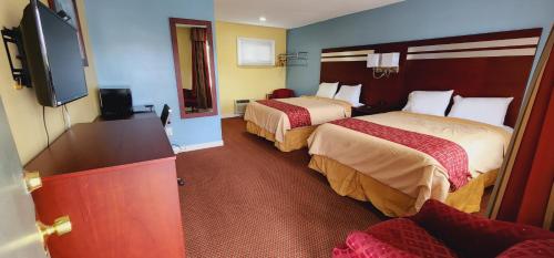 um quarto de hotel com duas camas e uma televisão de ecrã plano em Bassett Motel em Williamsburg