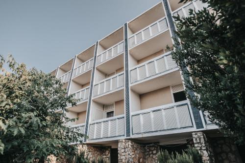 an apartment building with white balconies and trees at Colentum Resort Murter in Murter