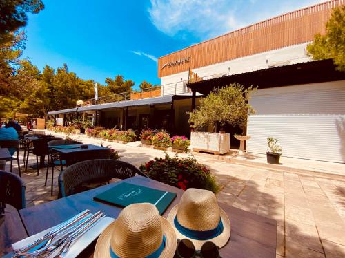 two hats sitting on a table outside of a restaurant at Zlatni Rat Beach Resort in Bol