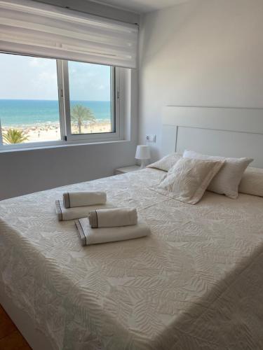 ein weißes Schlafzimmer mit einem großen Bett und Strandblick in der Unterkunft FRENTE AL MAR in Cullera