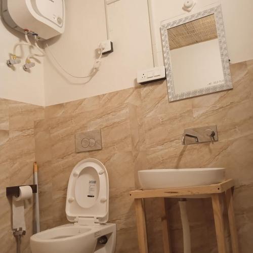 a bathroom with a toilet and a sink and a mirror at Living Good - A Himalayan Boutique Stay in Gushaini