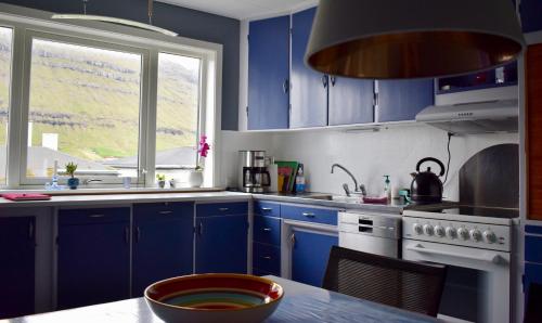 a kitchen with blue cabinets and a sink and a window at Brekkustova - Modern, cosy and spacious apartment in Klaksvík