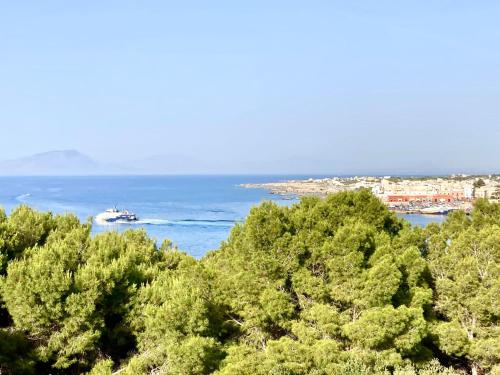 a boat in the water behind some trees at Dimora delle Tonnare in Favignana