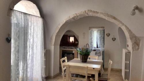 uma cozinha e sala de jantar com uma mesa e um arco em Trulli Manuela (il fragno) em Locorotondo