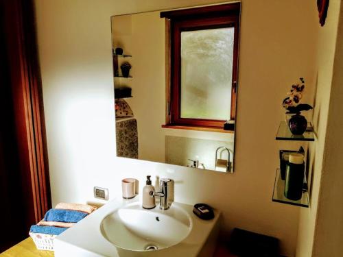 ein Badezimmer mit einem weißen Waschbecken und einem Spiegel in der Unterkunft La Vache Qui Roule -CIR Charvensod 0037 in Aosta