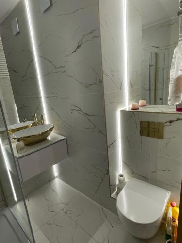 a white bathroom with a toilet and a sink at Apartament Lili Słoneczne Tarasy in Dziwnówek