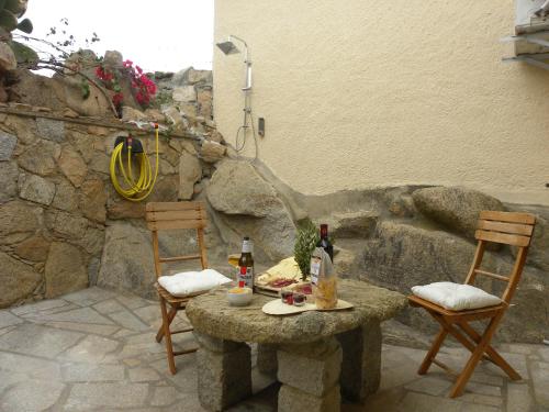 una mesa de piedra con dos sillas y bebidas en ella en Villa Carlotta la Maddalena, en La Maddalena