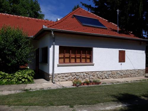 a white house with a red roof with a window at Manó Vendégház in Pázmánd