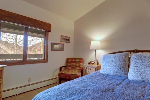 a bedroom with a blue bed and a chair and a window at CV210A Copper Valley Hotel Room condo in Copper Mountain