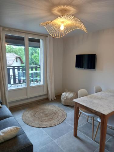 ein Wohnzimmer mit einem Tisch und einem Kronleuchter in der Unterkunft Le Loutin in Saint-Bonnet-en-Champsaur