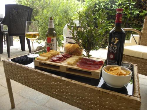 una mesa con una bandeja de comida y una botella de vino en Stanza privata con giardino, en La Maddalena