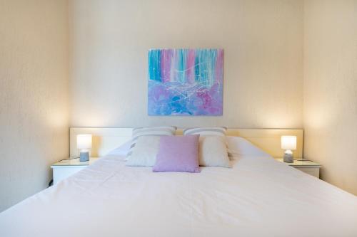 a white bed in a bedroom with a painting on the wall at Residence Poseidon in Spartia