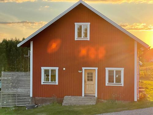 una casa roja con una puesta de sol en el fondo en Hälla 1 nära jönåkers golfbana, en Jönåker