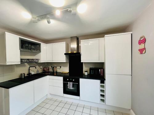 a kitchen with white cabinets and a black appliance at Blue Belgrave in Torquay