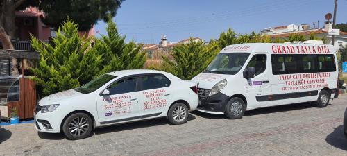 two white vans parked next to a small car at Grand Yayla Hotel in Cesme