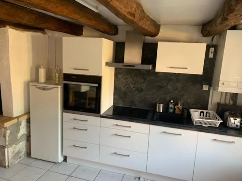 eine Küche mit weißen Schränken und einem Kühlschrank in der Unterkunft Petite maison lorraine avec cheminée et jardin in Saint-Mihiel
