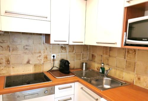 une cuisine avec un évier et un micro-ondes dans l'établissement Studio 1 - LES SUITES DE ROBINSON - Résidence avec piscine en bord de Siagne, à Mandelieu-La-Napoule, à Mandelieu-la-Napoule