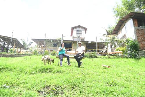 a man and a woman sitting on a bench with a dog at La Cigarra Casa de Huéspedes in Salento