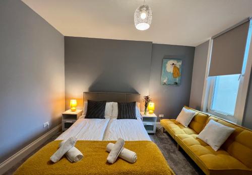a bedroom with a bed and a yellow couch at Blue Belgrave in Torquay