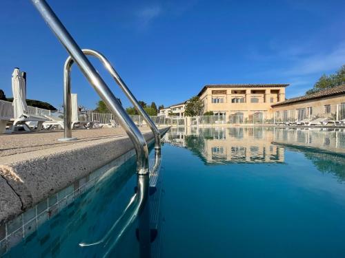 uma piscina de água com um edifício ao fundo em Studio 1 - LES SUITES DE ROBINSON - Résidence avec piscine en bord de Siagne, à Mandelieu-La-Napoule em Mandelieu-la-Napoule