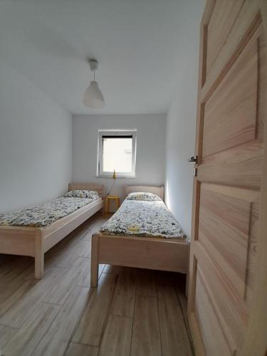 two beds in a room with a door and a window at Domki u Karola Domek nr 1 in Mikołajki