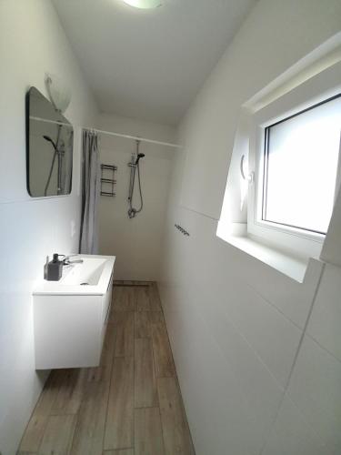 a white bathroom with a sink and a window at Domki u Karola Domek nr 1 in Mikołajki