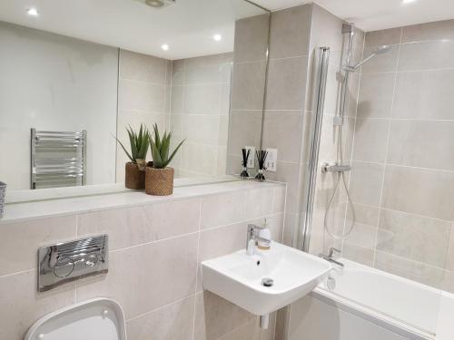 une salle de bain blanche avec lavabo et douche dans l'établissement Luxury City Apartment in JQuarter Birmingham, à Birmingham